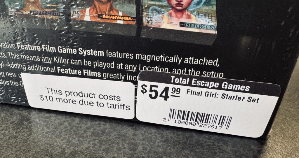 A board game with two stickers, one showing the price and one listing the increase due to tariffs.