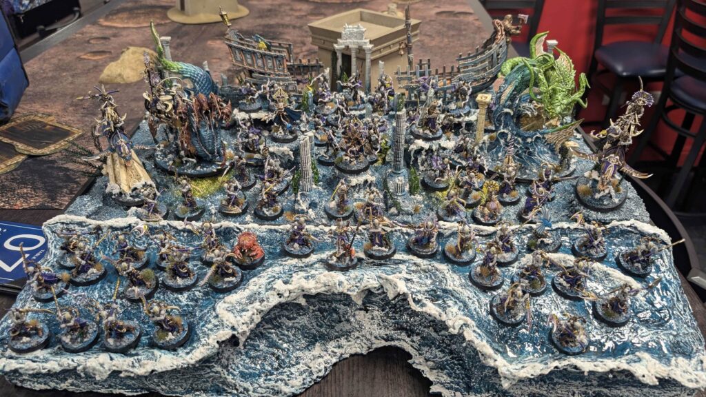 A beautiful diorama of Idoneth Deepkin miniatures including a sunken ship and other set dressing.